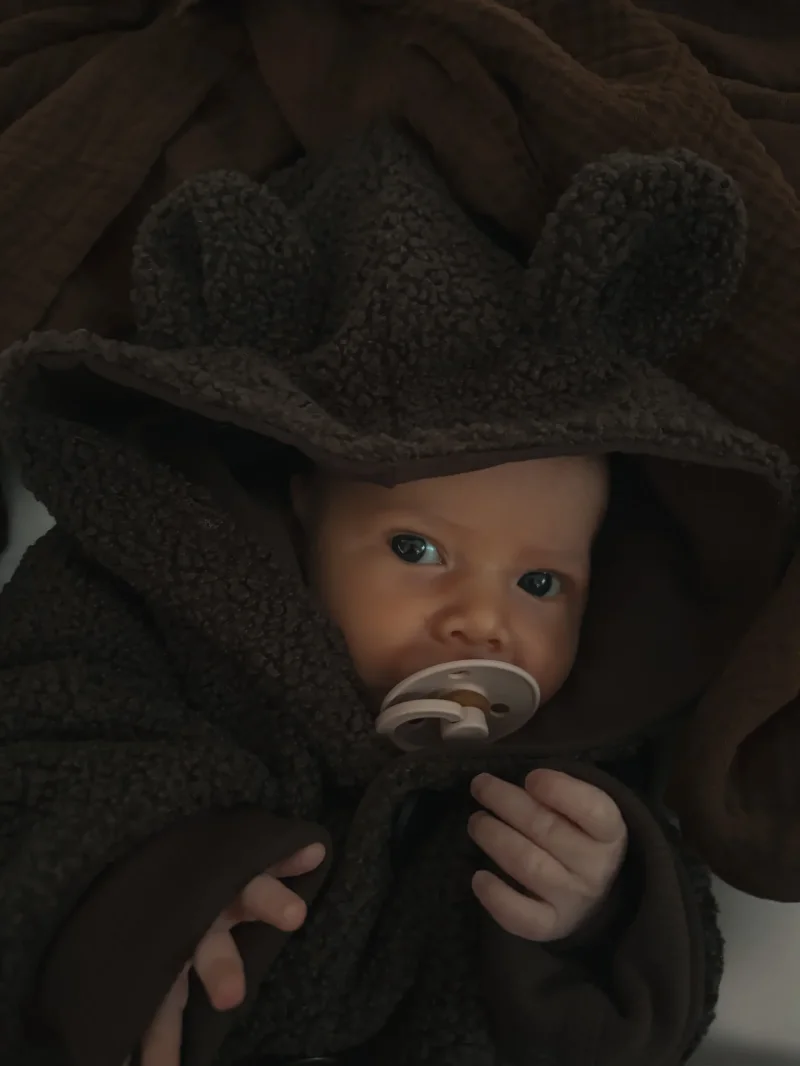 Detaillierte Ansicht der Bärenohren an der Kapuze eines dunkelbraunen Bouclé Kinderoveralls